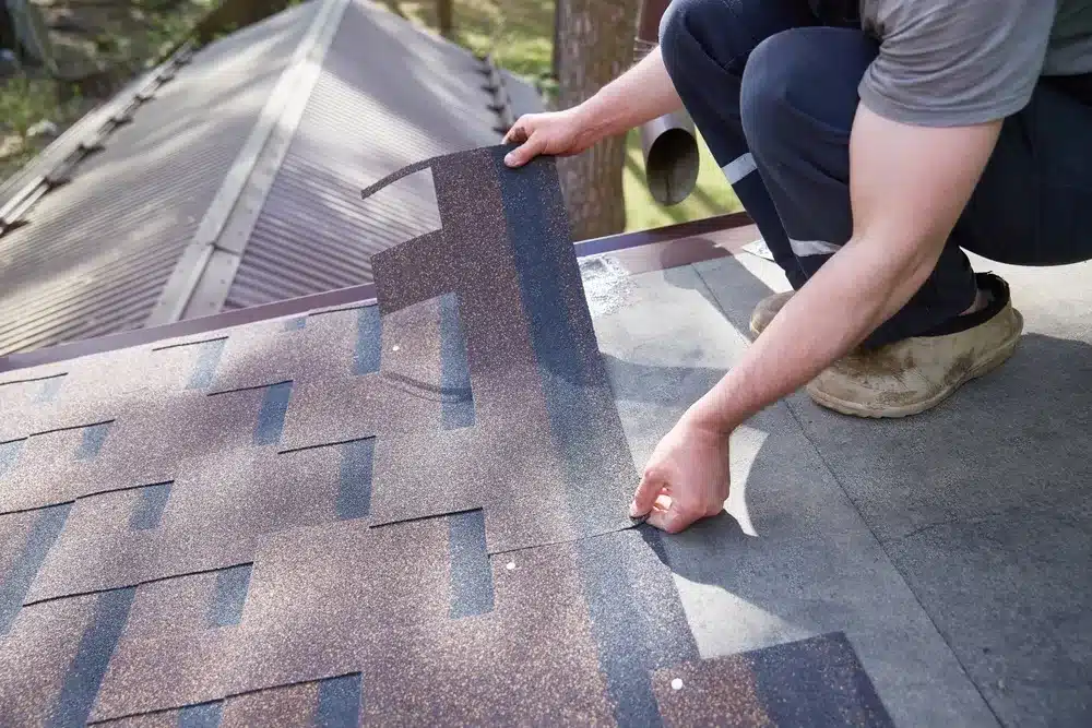 A roofer carefully aligning and installing architectural asphalt shingles on a rooftop