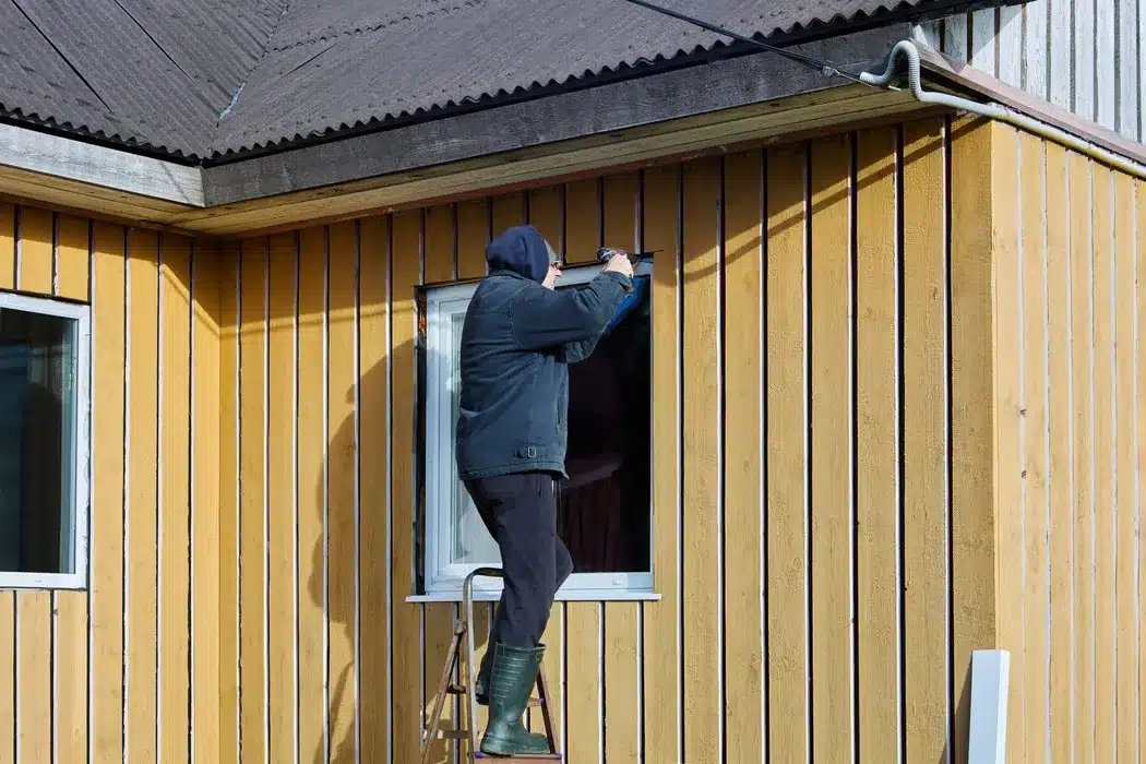 Contractor trimming siding around window on Bristol house scaled