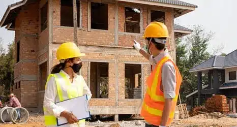 Contractors discussing brick home framework at Bristol construction site