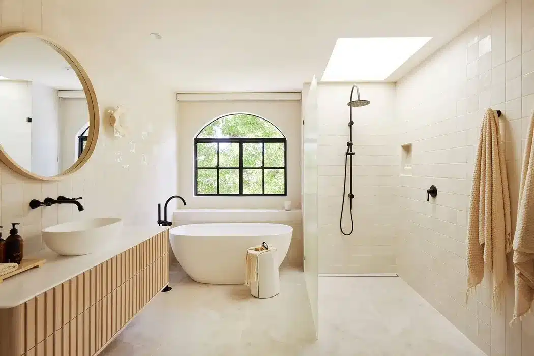 Minimalist bathroom with tub, open shower, and arched window