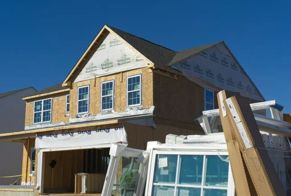 Partially constructed house with exposed plywood and window framing, prepared for siding installation