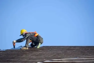 Roofer fastening tiles during roofing work in East Providence