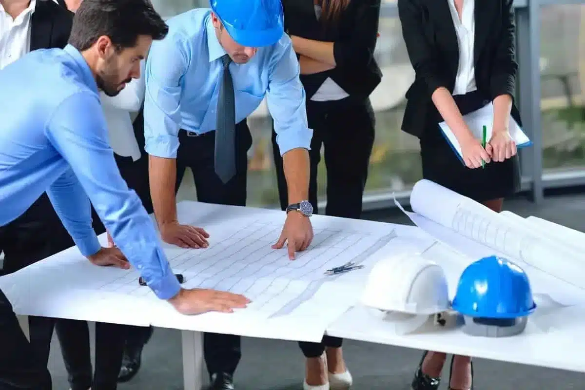 Team reviewing construction blueprints at a table with safety helmets.