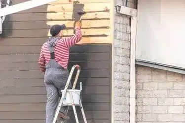 Worker painting new siding on a Bristol homes exterior