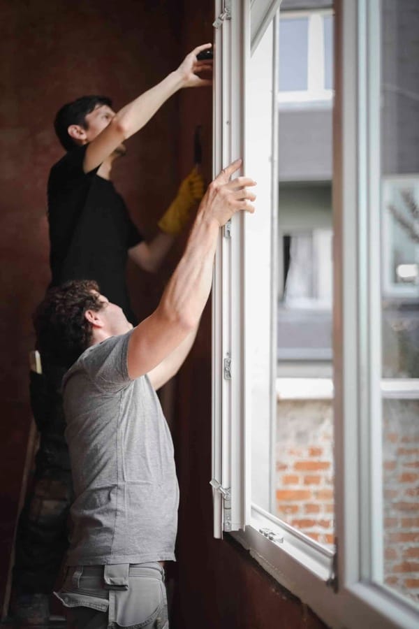 two young people installing window in East Providence