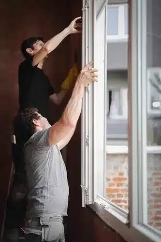 two young people installing window in East Providence