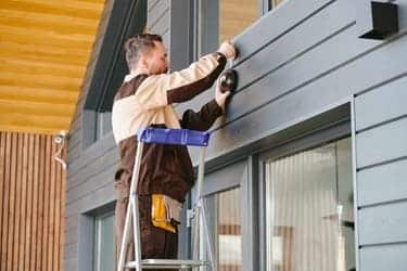 a man repairing the siding of house in providence