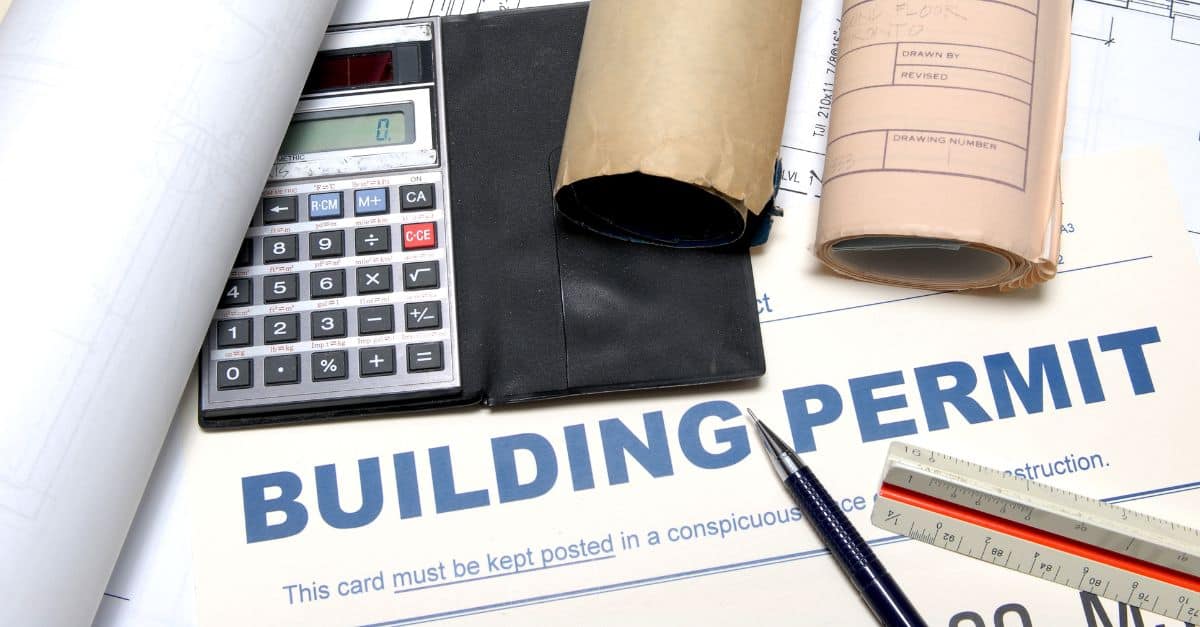 A paper written building permit, calculator and papers on side