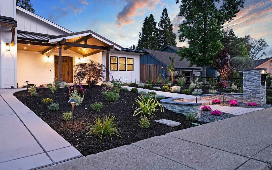 Modern home with front porch, landscaped yard, and outdoor lighting at sunset