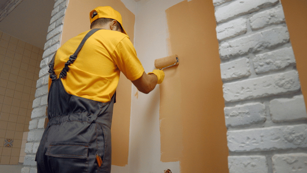 A worker painting a wall with a paint roller