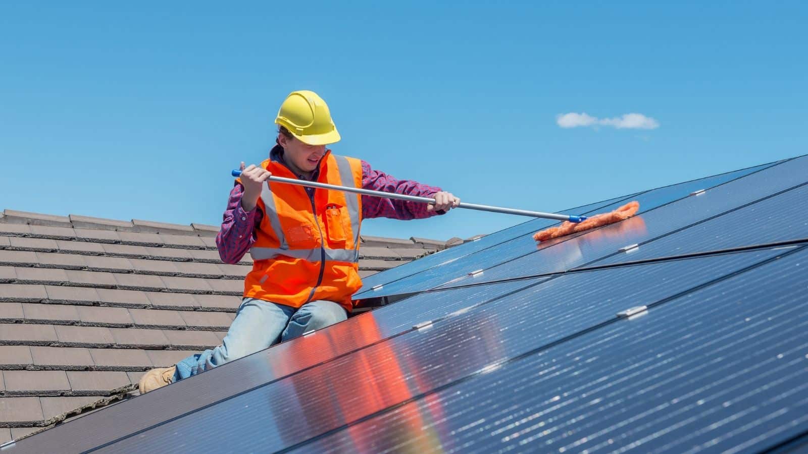 a female roofing expert cleaning the solar panels