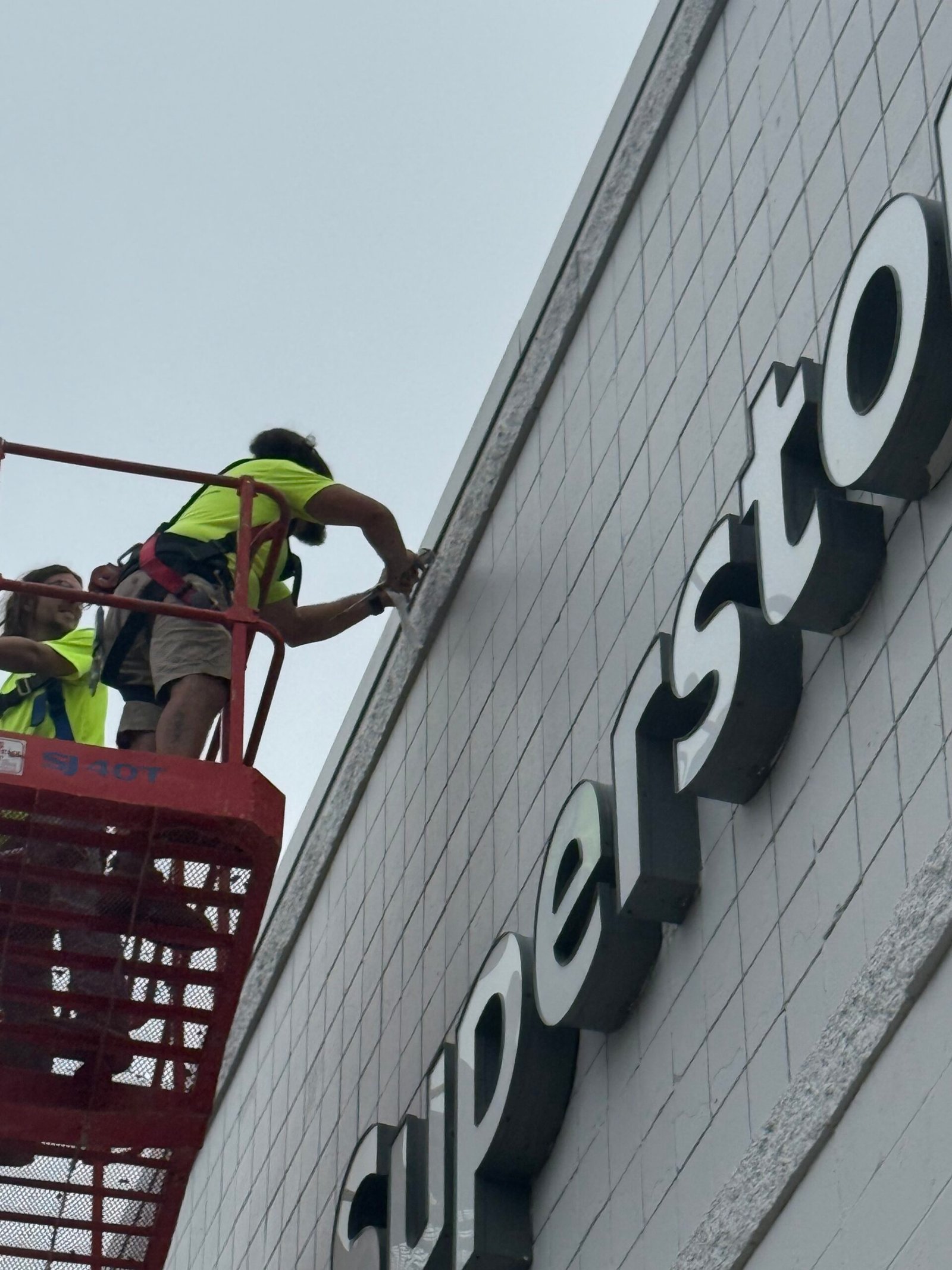 Building envelope consultant inspecting exterior CMU wall from an aerial lift