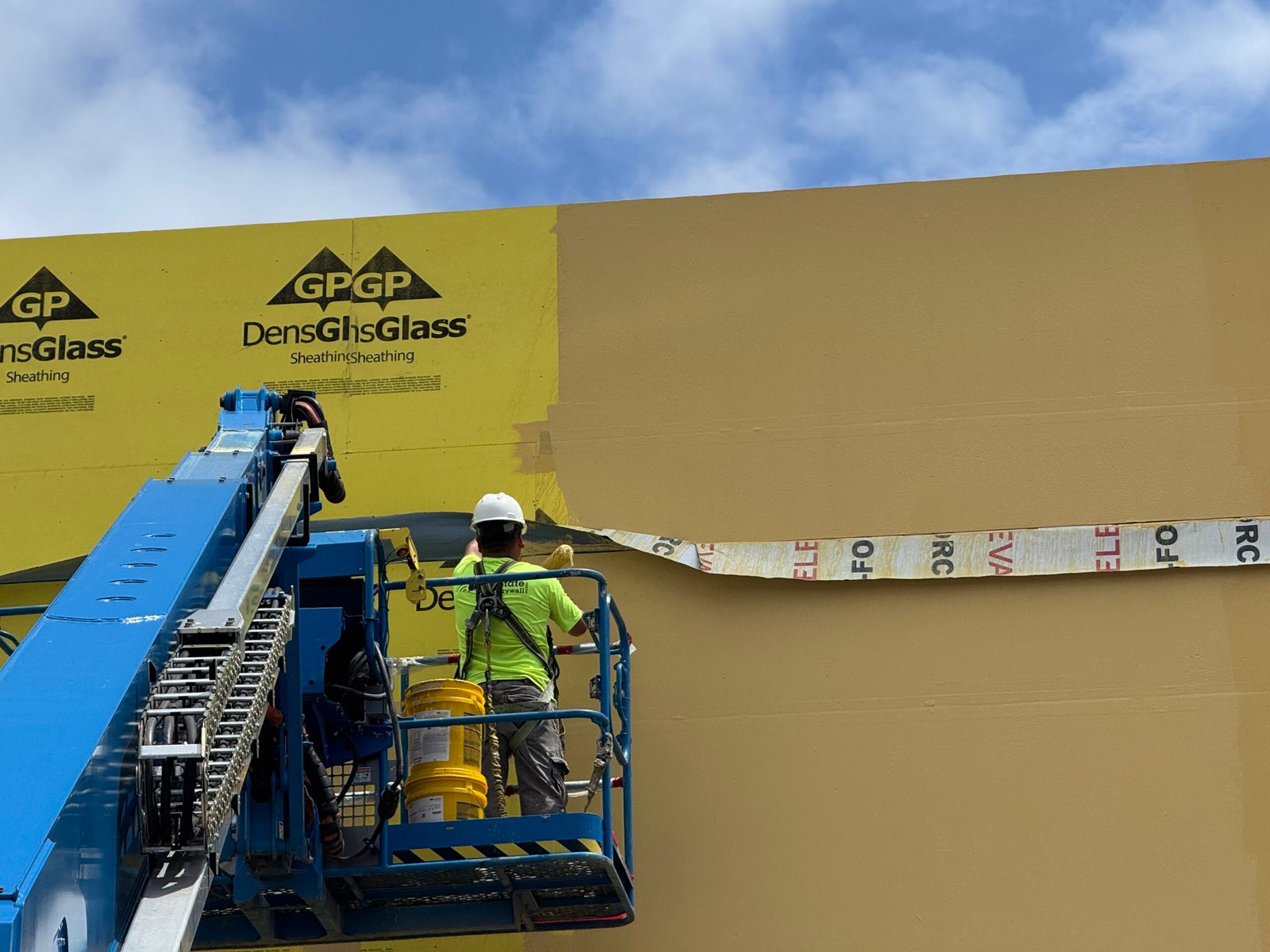 Building envelope repair work being observed from an aerial lift during construction.